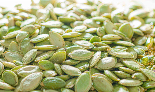 Extreme macro of raw green pumpkin seeds in shallow focus catching raking morning light