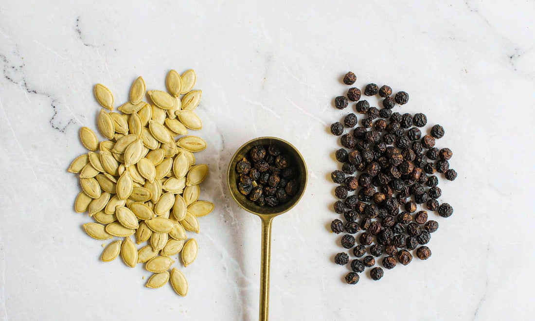 Pumpkin seeds and dried saw palmetto berries side by side on a bright white surface