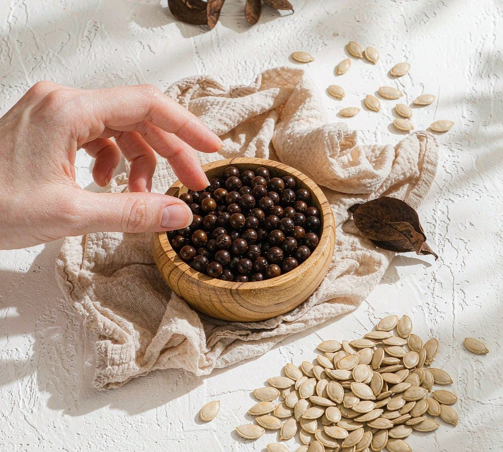Pumpkin seeds and saw palmetto berries in a wooden bowl, bright airy flat lay