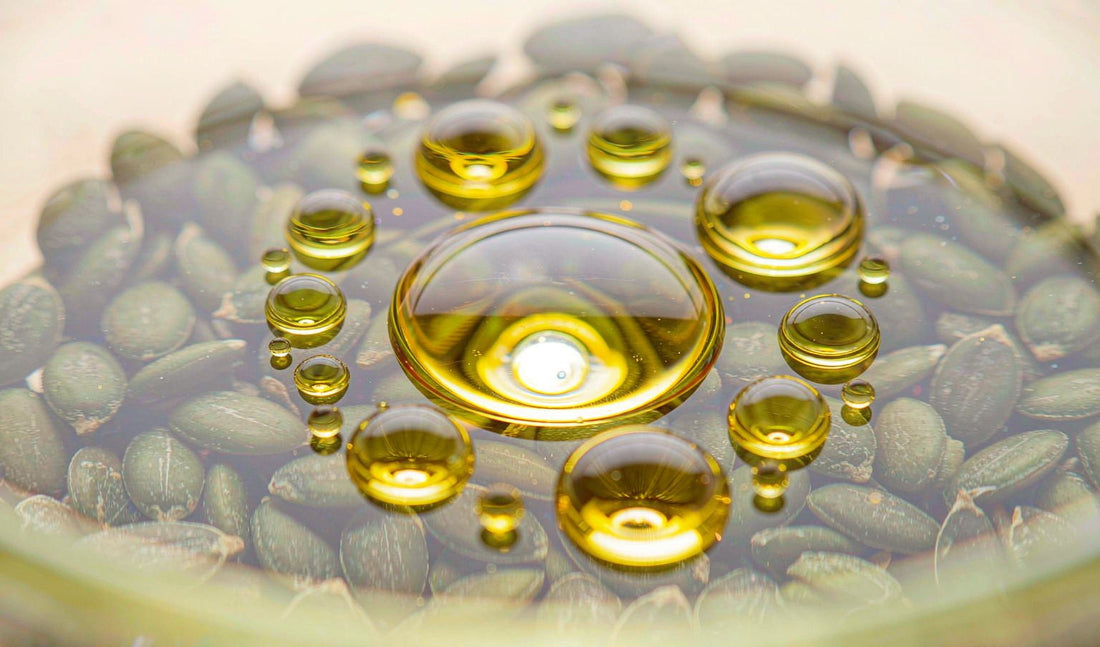 Extreme macro of golden pumpkin seed oil droplets on a bed of green pumpkin seeds in warm light