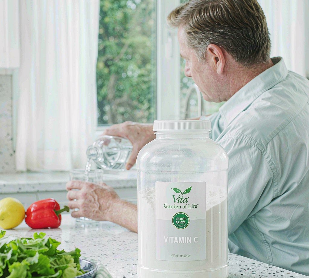 A man in his 50s seen from behind at a bright airy kitchen counter, no face visible